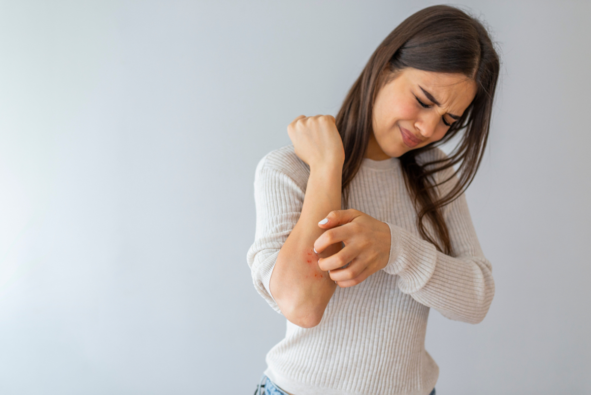 Woman crab arm on gray background. Psoriasis symptoms. Woman scratching arm.