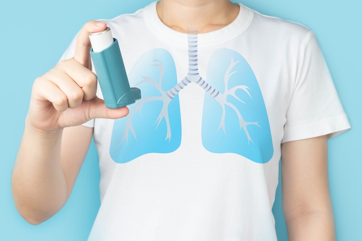 Young woman using blue asthma inhaler for relief asthma attack. Pharmaceutical products is used to prevent and treat wheezing and shortness of breath caused asthma or COPD. Lung organ anatomy.