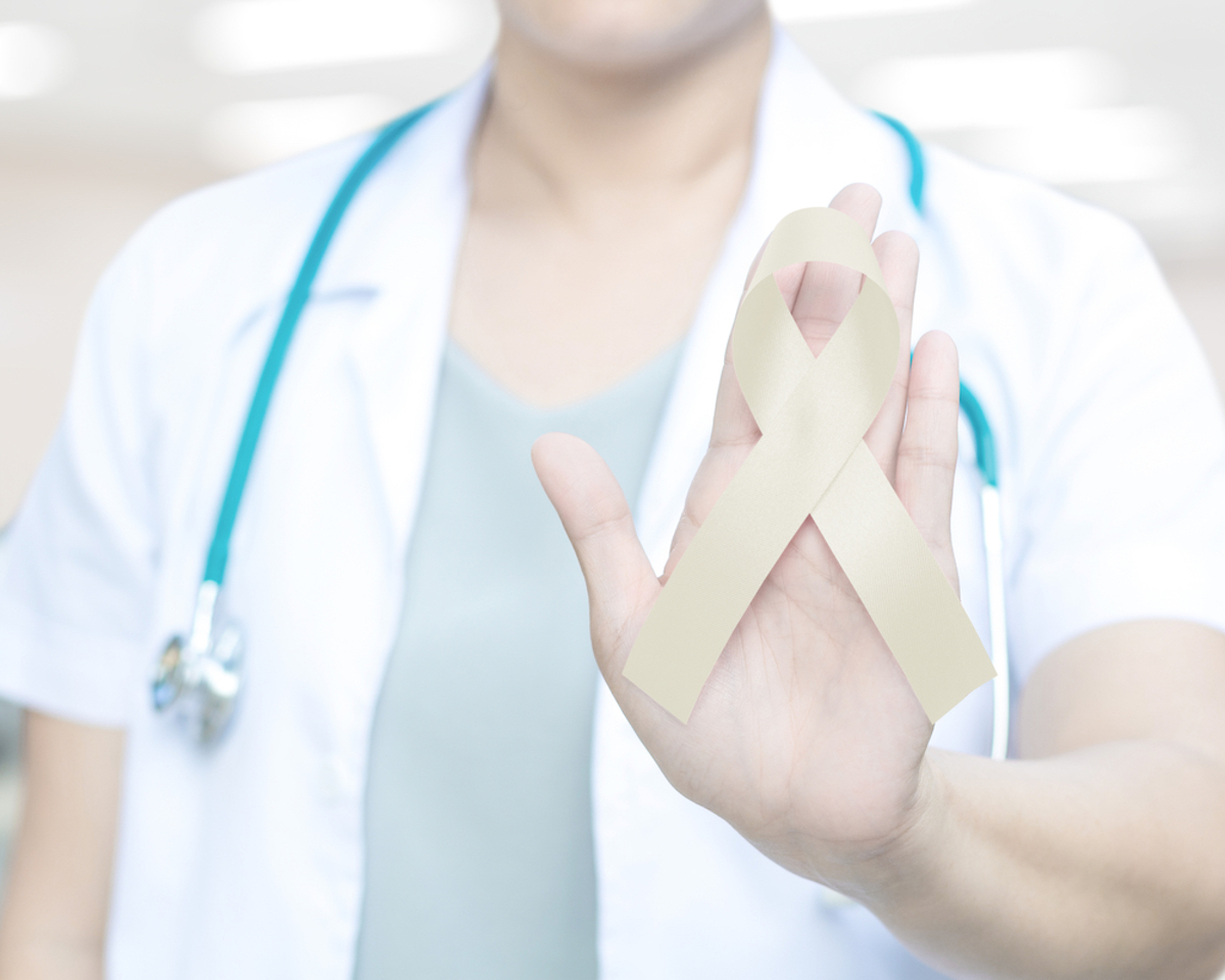 Female doctor in white uniform with cream ribbon awareness in hand for Paralysis, Spinal Cord Injuries (SCI), Spinal Diseases & Disorders, Healthcare concept.