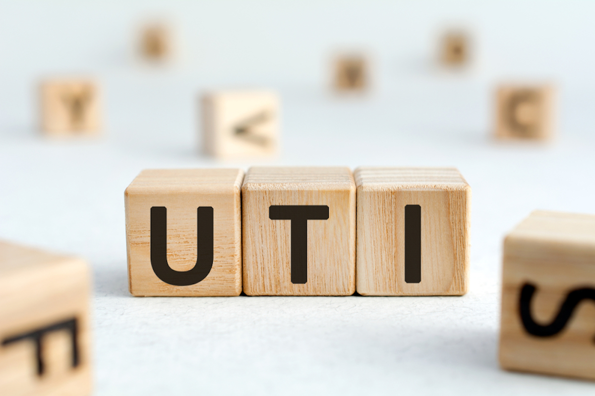 UTI - acronym from wooden blocks with letters, abbreviation UTI urinary tract infection, concept, random letters around, white background 
