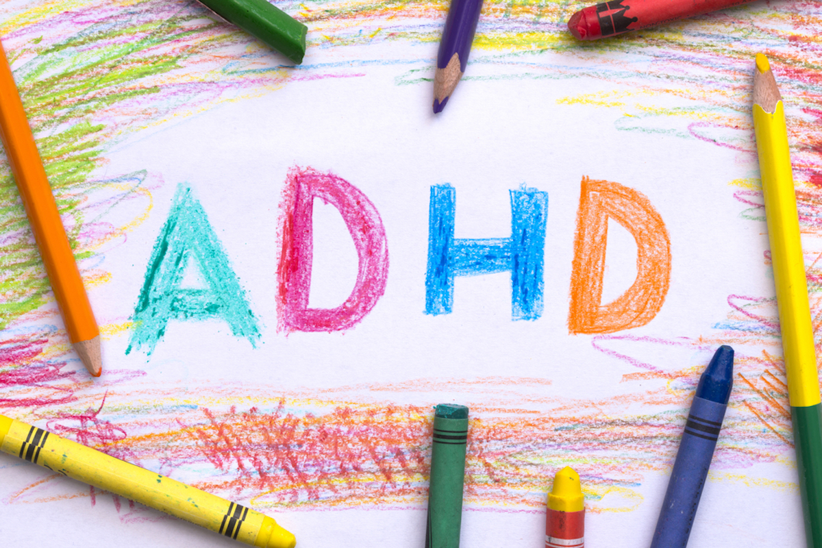 ADHD illness concept with word written with colored crayons on white paper sheet
