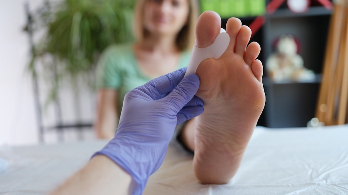 Doctor holds brace for hallux valgus. Pain in toes can be caused by broken bone tendinitis sprain gout arthritis or bone disease concept
