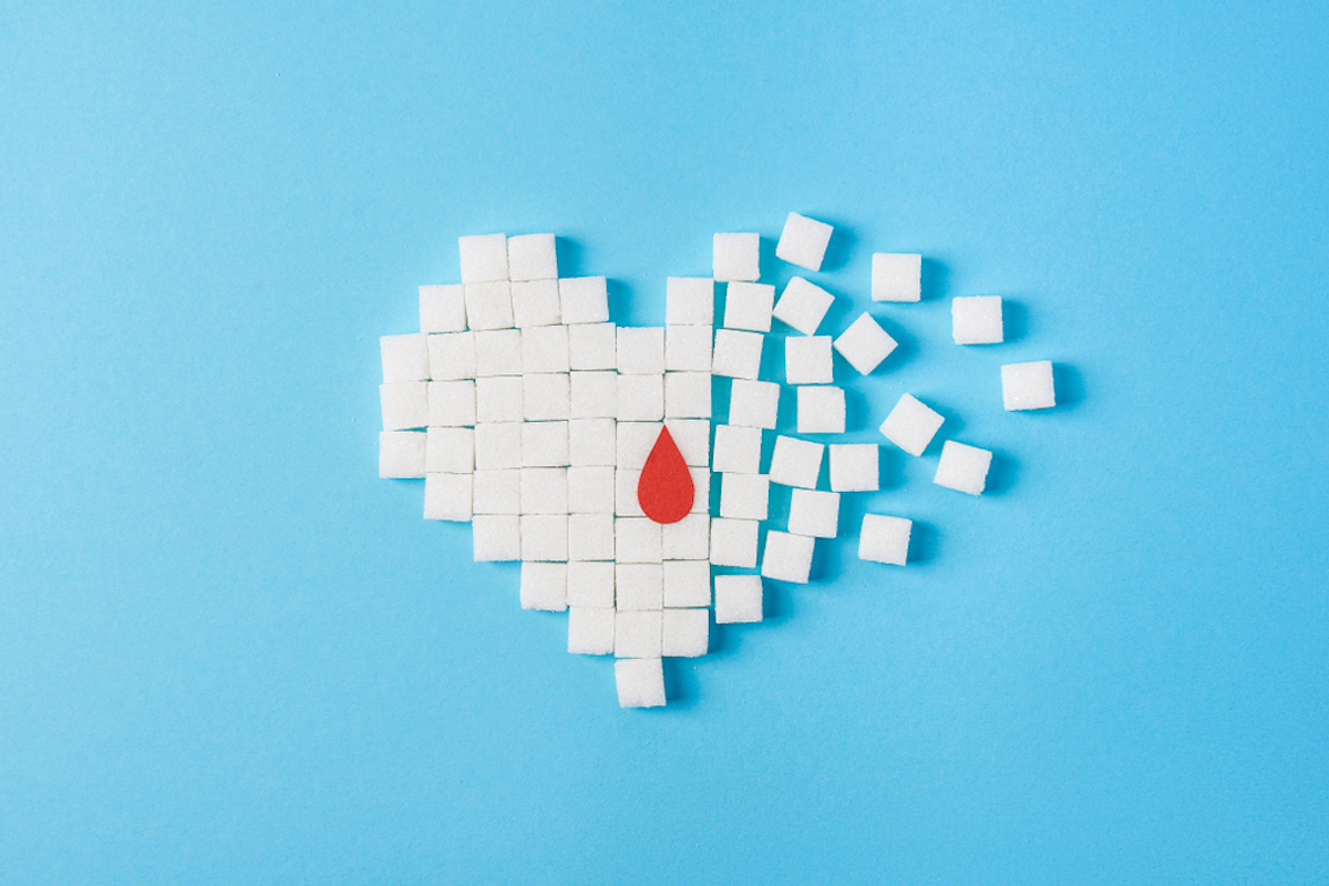 the drop of blood on broken heart made of pure white cubes of sugar isolated on blue background, World Diabetes Day, Nov. 14. What are normal blood sugar levels?