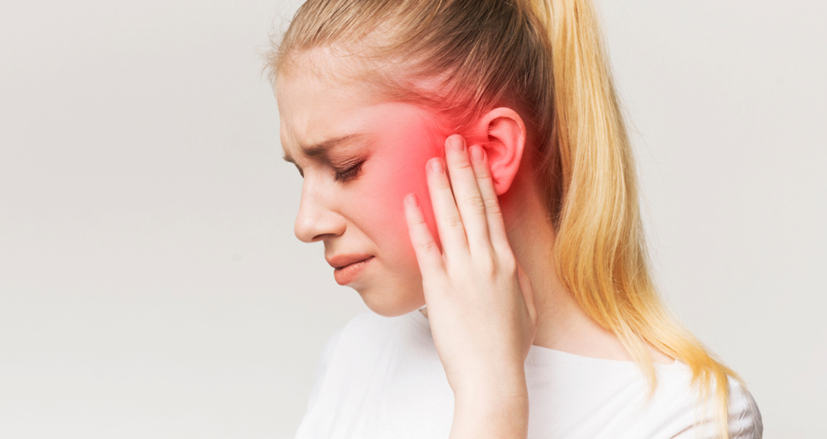 Tinnitus. Profile of a sick woman with ear pain, touching her aching head, panorama